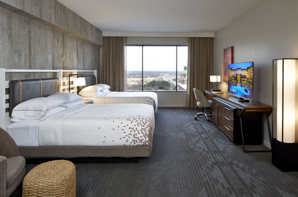 hotel room with lare double bed laid out with white sheets and coverlet.
