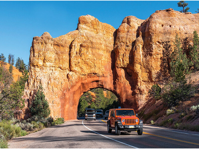 An arch dug through a high redrock mountain for the highway to pass through