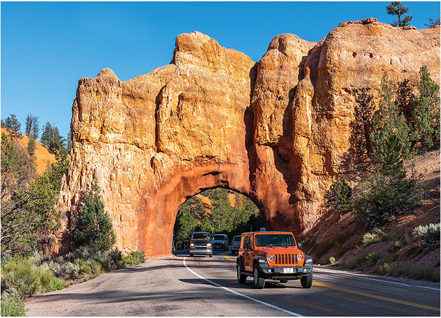 An arch dug through a high redrock mountain for the highway to pass through