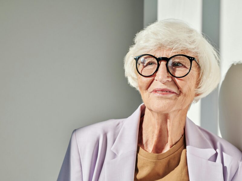 older lady with black glasses and white hair with bangs.