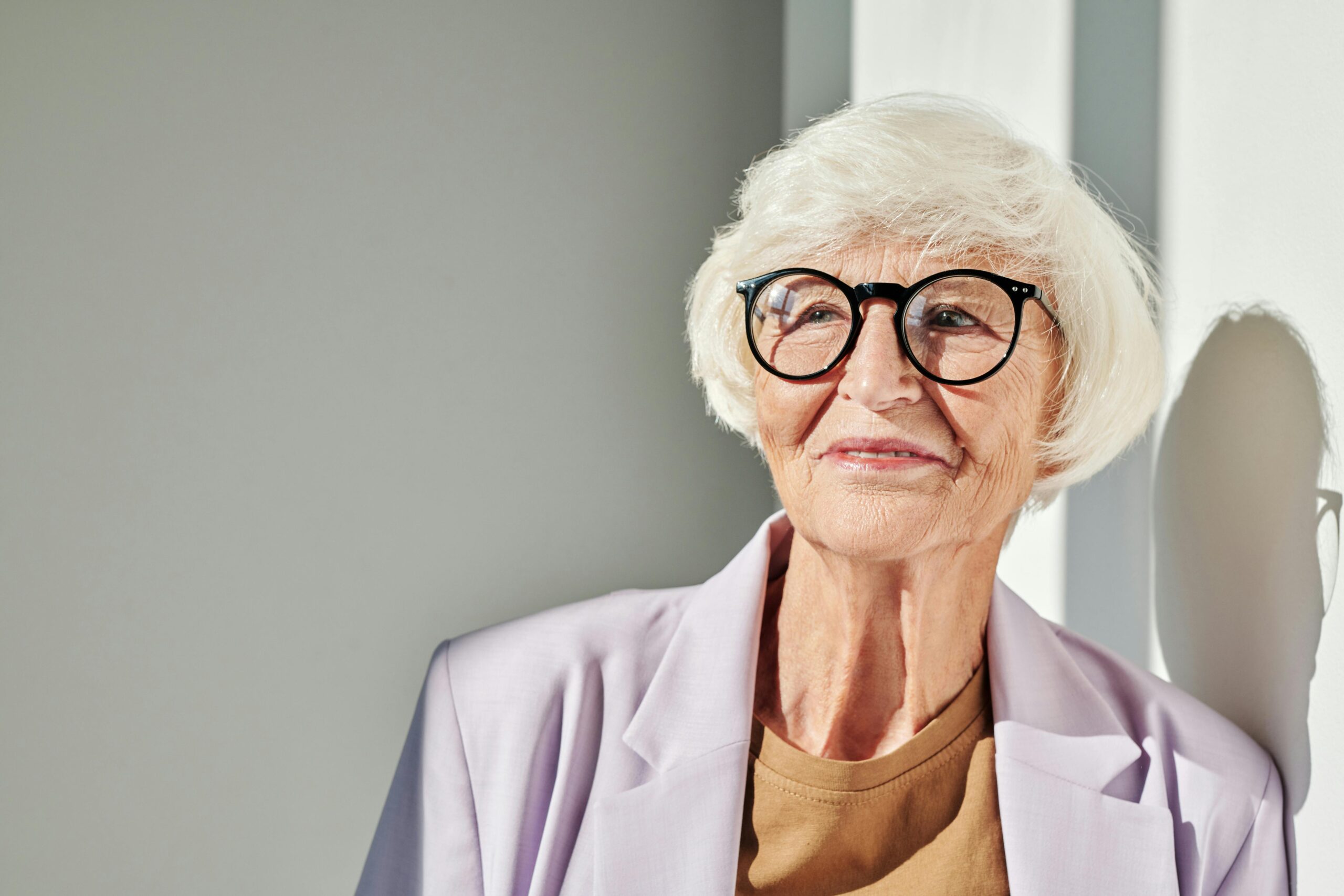 older lady with black glasses and white hair with bangs.