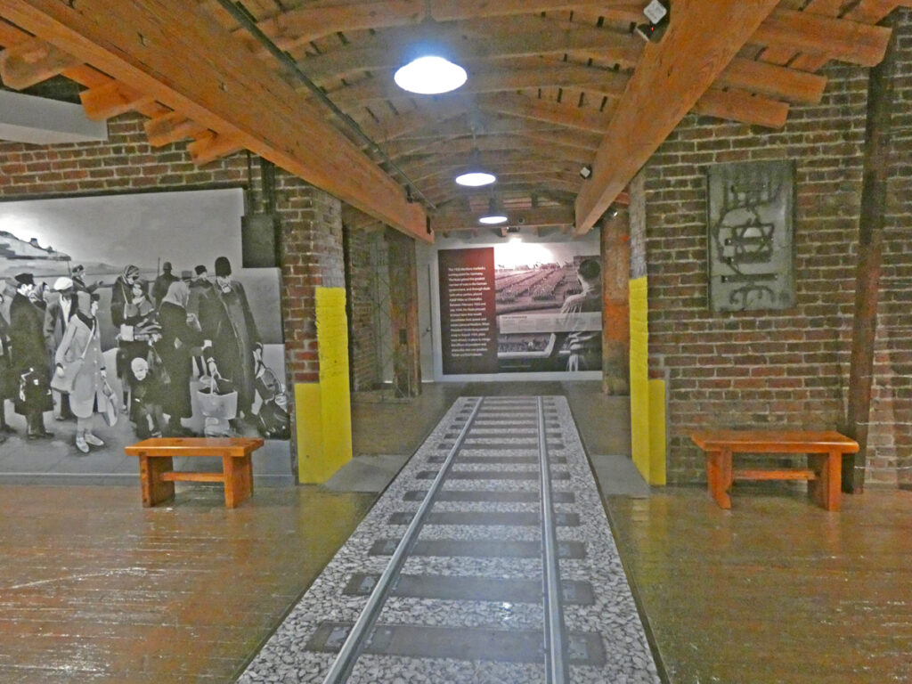 a pathway that looks like a railroad track carpet inside a pine room with hellow posts from floor to ceiling