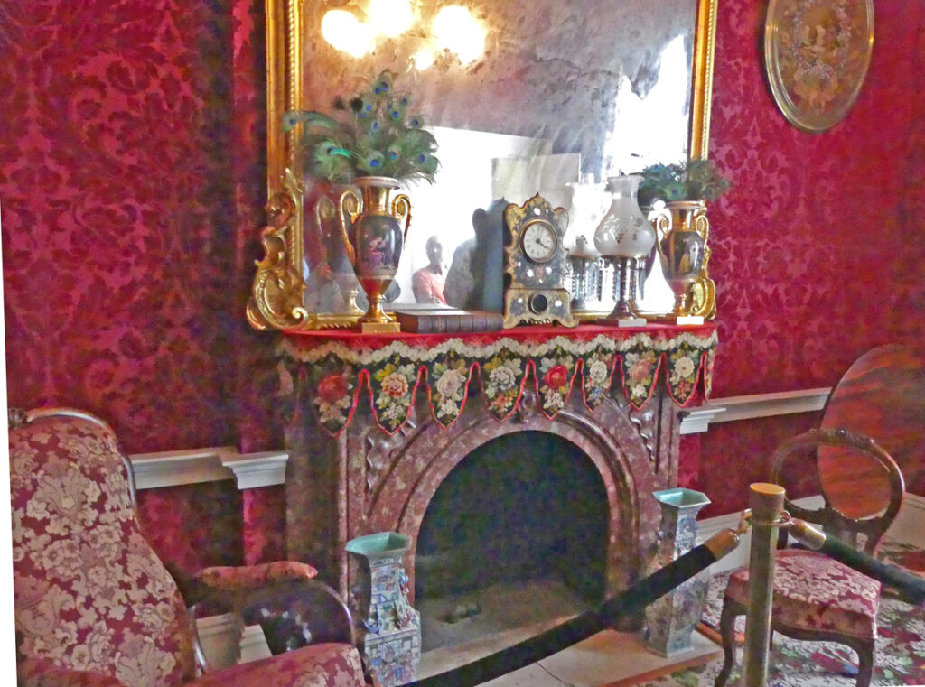 a red fireplace with large mirrow hung overhead against red wall. 