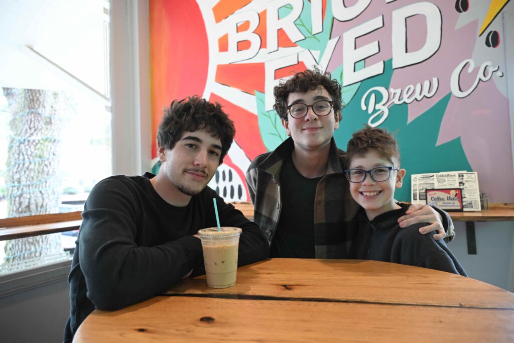 three teen boys sitting at a round table in a brightly colored restaurant