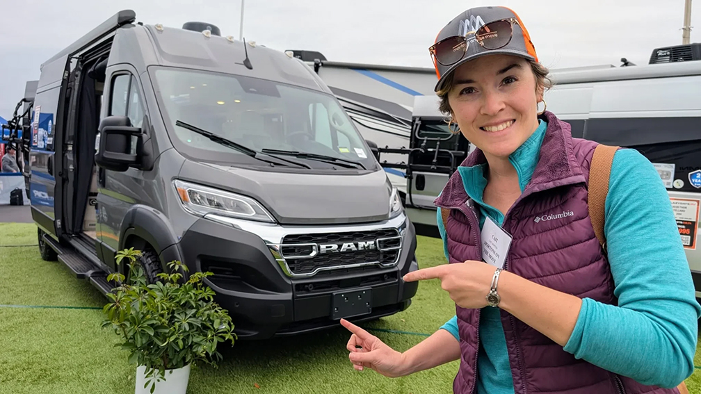 Someone standing in front of and pointing at an RV rental