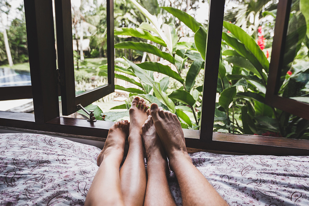 post_tropical_garden_outside window with a couple's bare feet showing on a bed in front of the window