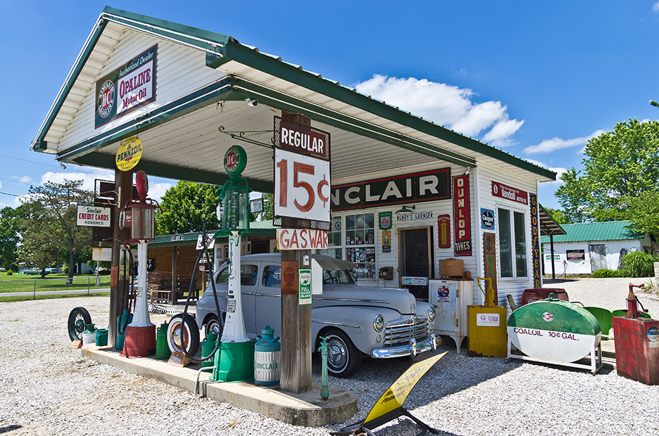 a 1950s era gas station with a poster listing gas at only 15 cents per gallon. 