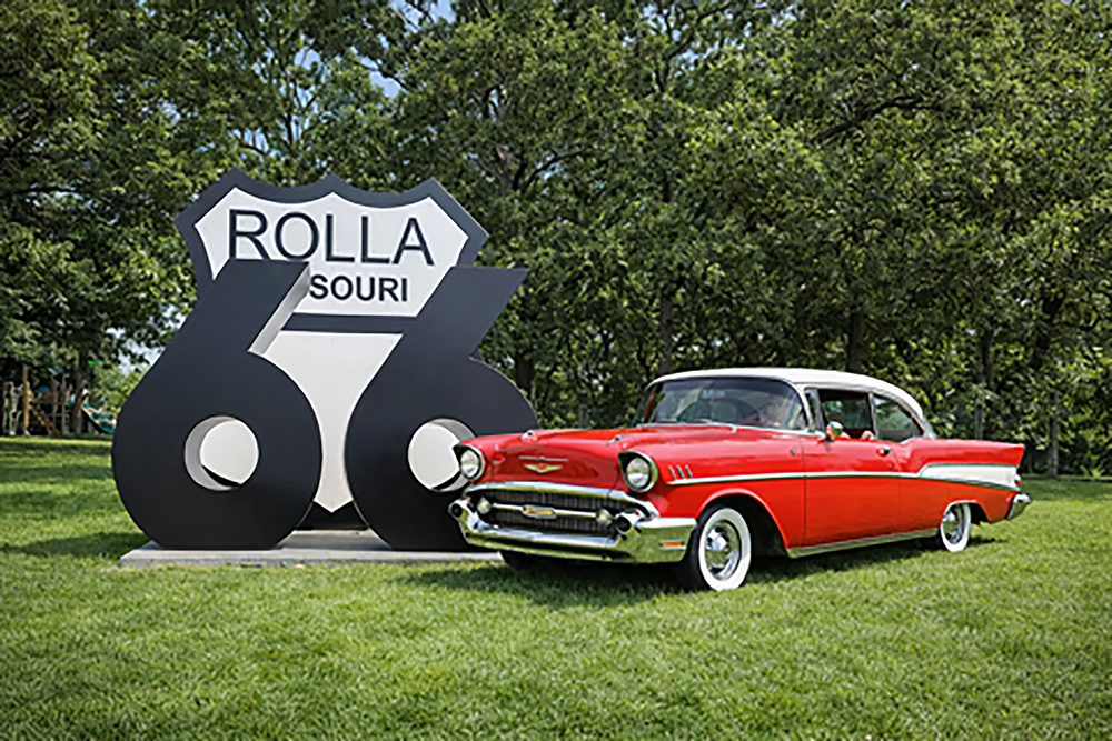 A huge Ret 66 sign with red chevy parked in front of it