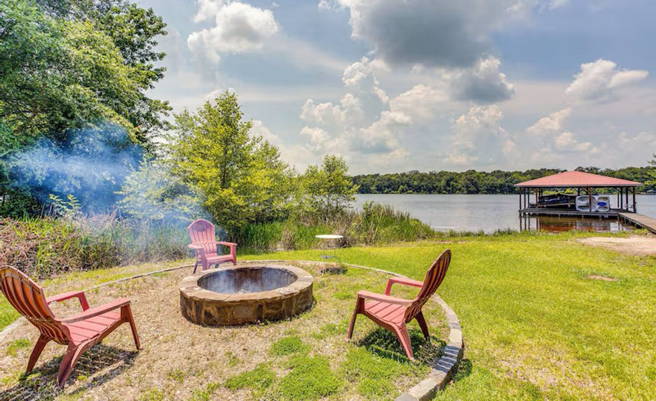 back yard next to lake, with circle bordere around campfire grill and lawn chairs