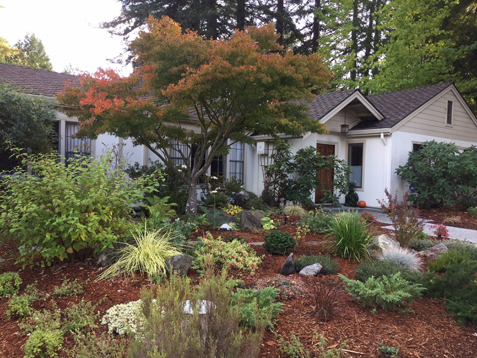flower garden placed in front yard of beautiful waterfront house with peaked roof