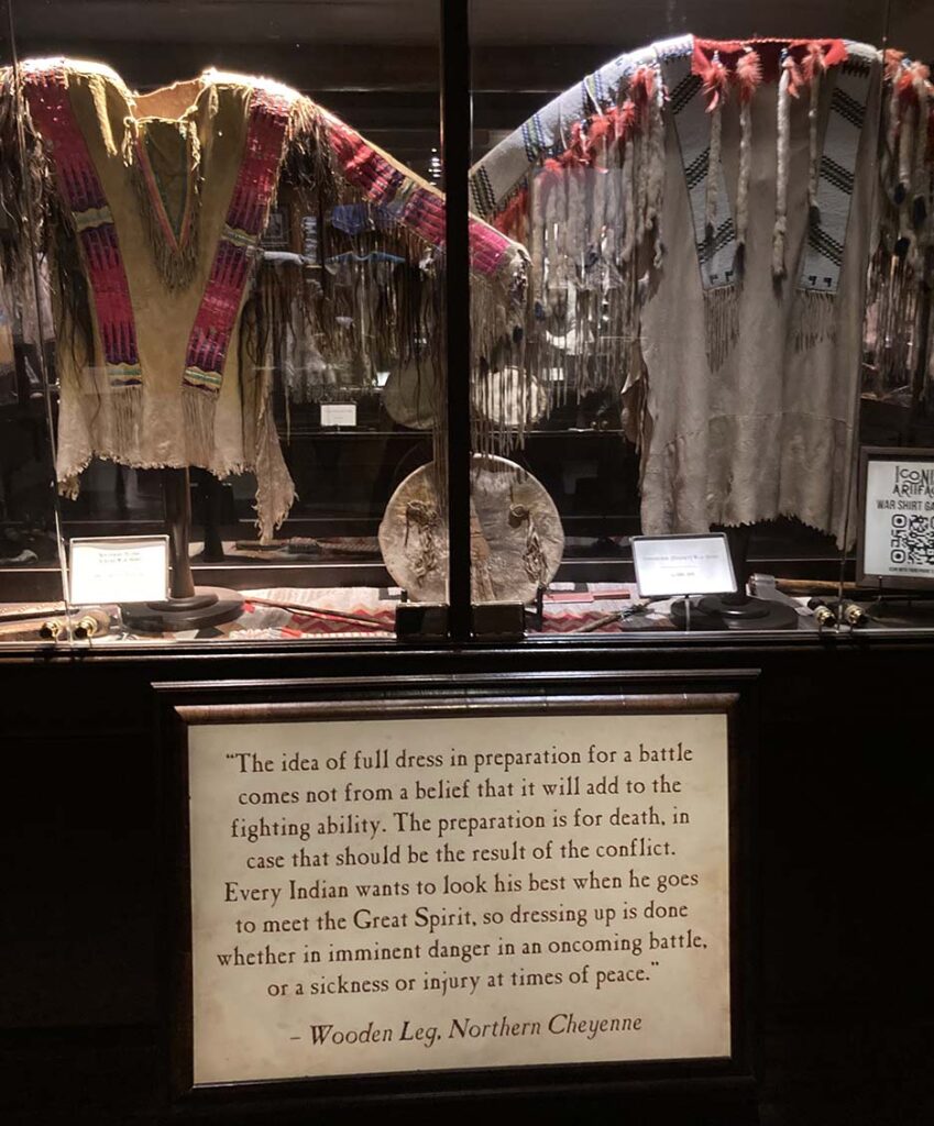 Native clothing on a stand in a museum behind glass 