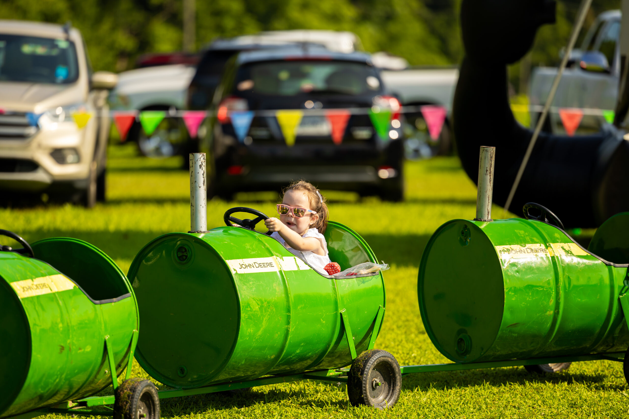 A girl with glasses riding in a green barrel. 