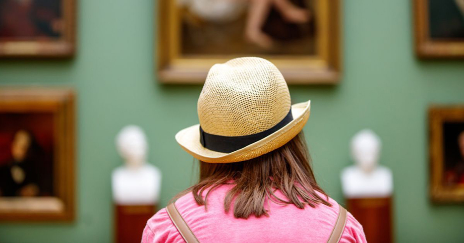 Someone wearing a hat looking at art in a museum