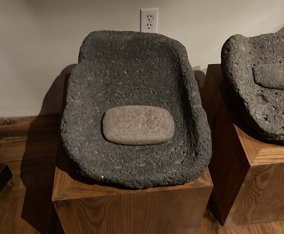 a smaller stone laying inside a cradle shaed rock fro grinding grain 