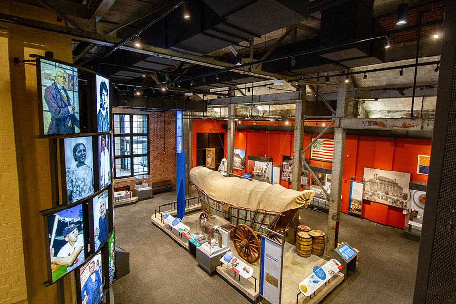a red room filled with memorabilia. In center is a replica of a small covered wagon.