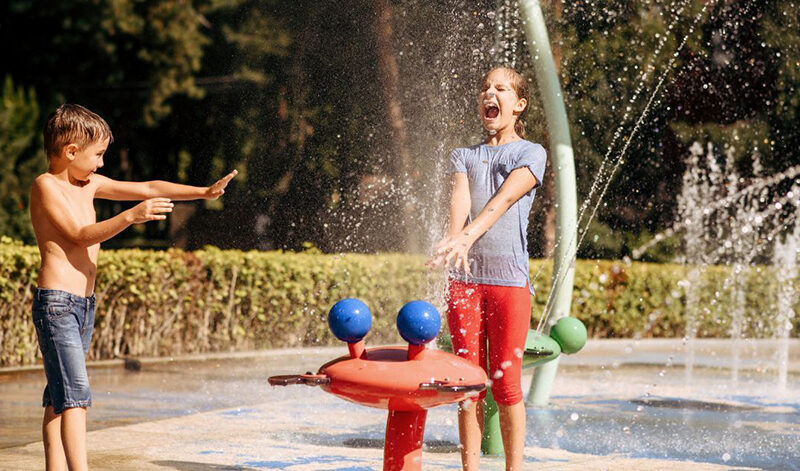 two boys playing outside with a water sprinkler