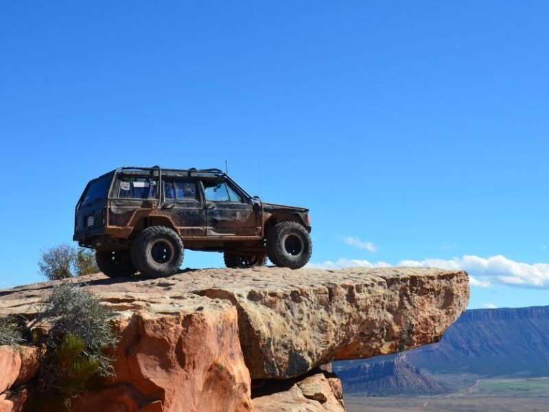 a black jeep facing to the right on a large rock cliff