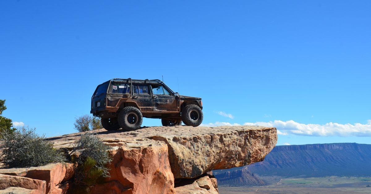 a black jeep facing to the right on a large rock cliff