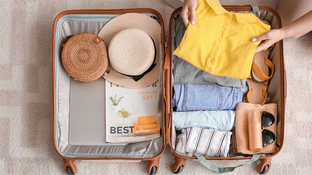 an open suitcase packed with folded summer clothes