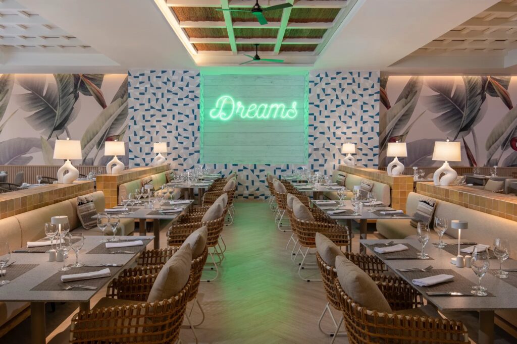 a bar with white small lanterns over the tables. The back wall has "dreams" written in cursive green lights lettering
