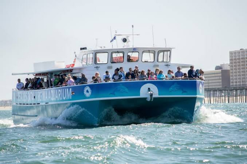 a full-sized tour boat with guests on  the water