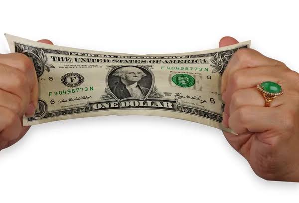 two hands pulling ends of a dollar to stretch a dollar