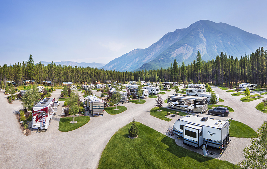 a full koa mobile campground in Montana at Glacier Natl. Park with a view of a peak mountain behind it. 