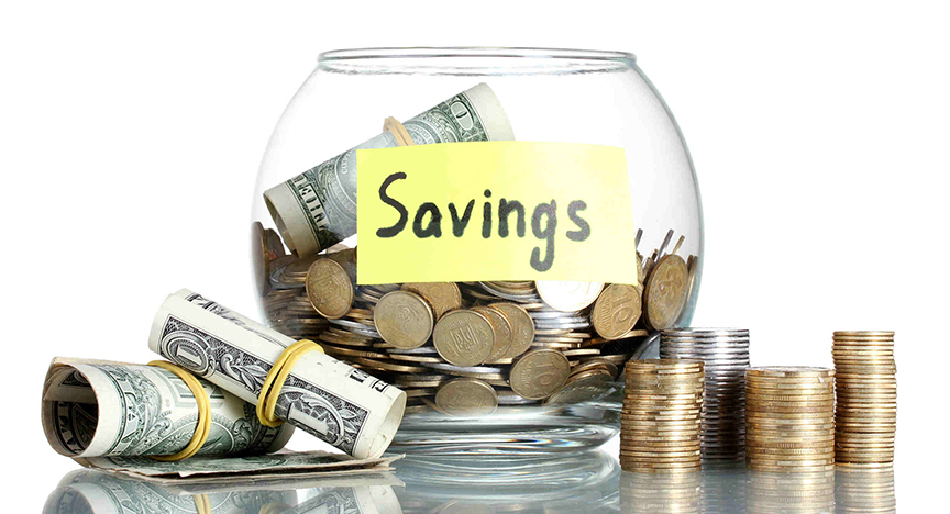 A round glass bowl half full of loose changeand a roll of dollar bills laying on top. Stacks of change are arranged beside the bowl on right and two rollsof dollar bills are laying at the left of the bow.

