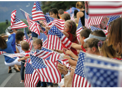 People wave flags as the Independence Day parade rolls down Main Street, Friday, July 4, 2014, in Eagar, Ariz. The Northern Arizona town celebrates the Fourth of July annually with a parade and fireworks. (AP Photo/Matt York)